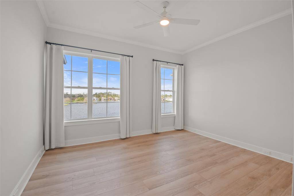 Lake views flank this guest suite bedroom with luxury vinyl flooring, two windows with linen curtains, new paint and updated fan with lighting.