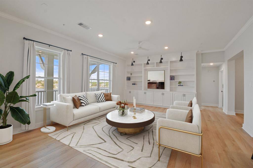 This spacious living room with beautiful windows, boasts a custom built-in with updated sconce lighting perfect for storage and can house your TV. * Virtually staged.