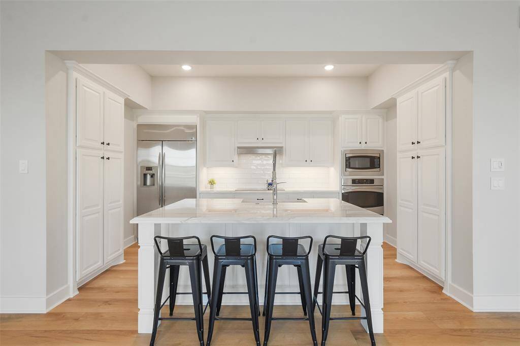 Centrally located is the magnificent kitchen with updated LED lighting, paint, backsplash and stunning countertops. An abundance of cabinets and double pantries offer ample storage. The oversized island provides additional bar seating.