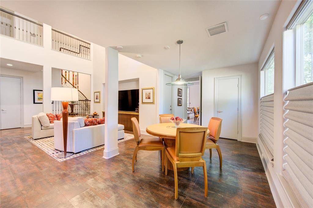 This open and airy breakfast space features a cozy seating area with soft modern style, a large picture windows with reverse shades for natural light. The neutral tones and flooring create a warm and inviting atmosphere.