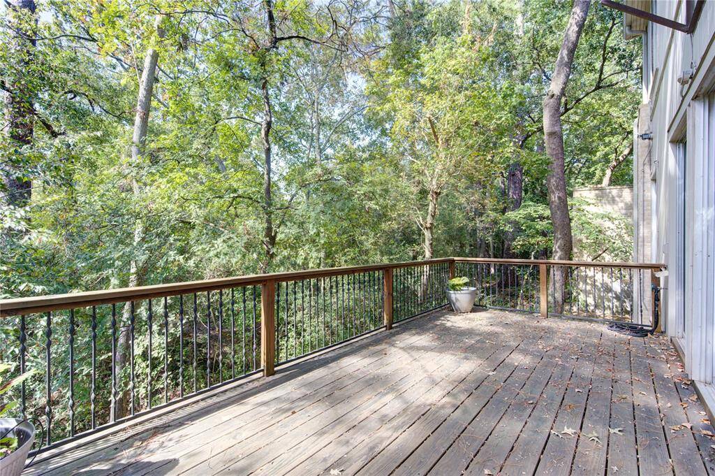 Incredible wooden deck with a railing, surrounded by lush trees, offering a peaceful and private outdoor space ideal for relaxation or entertaining.