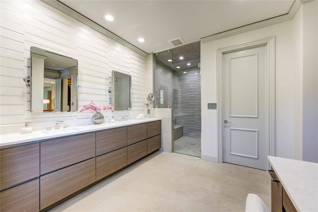 Another view of the primary bathroom showing the large walk-in shower with glass doors. The light color palette and recessed lighting create a bright, inviting atmosphere. Door leads to private commode room.