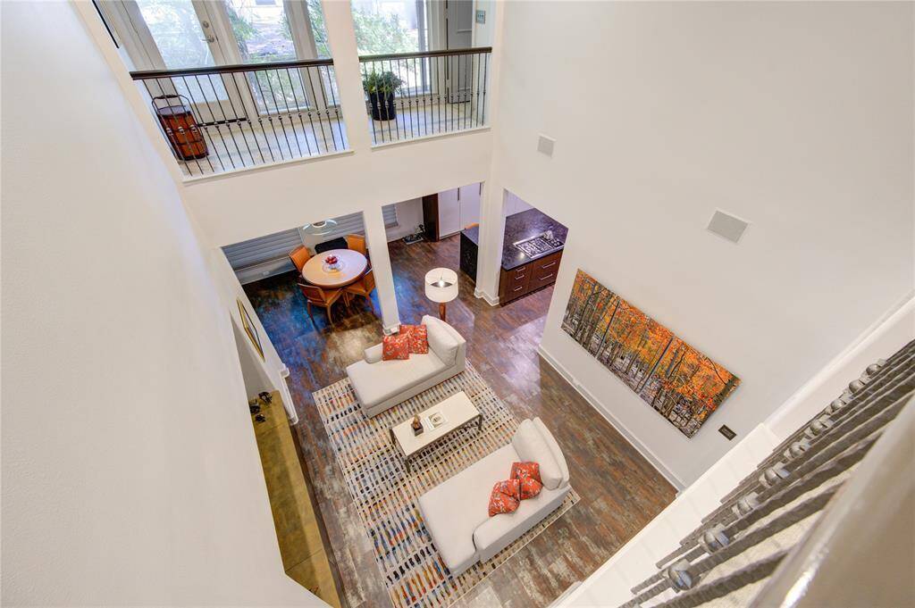 This photo showcases a modern, open-concept living area with high ceilings and a view of the upstairs interior Juliet balcony. Large French style windows provide loads of natural light.