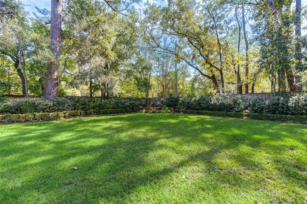 Neighborhood park in cul-de-sac with lush grass, surrounded by mature trees and neatly trimmed shrubs, offers the perfect spot to walk your furry friend.