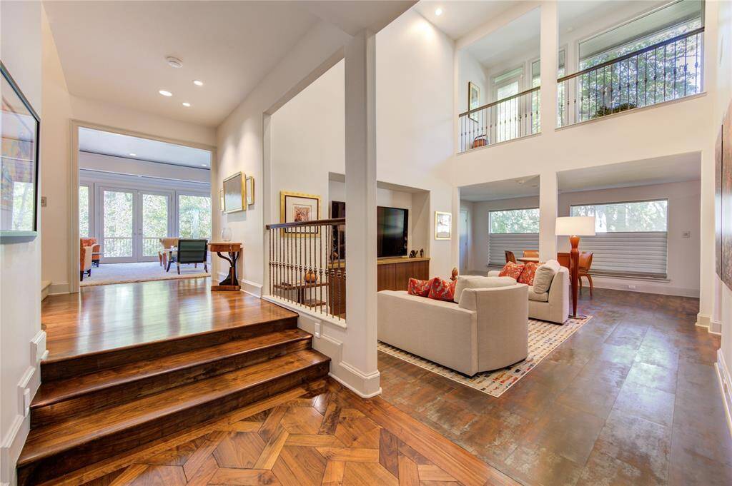 This home features an open floor plan with high ceilings and abundant natural light. The family area, with a cozy seating arrangement, overlooks a breakfast space with picture windows, offering a warm and inviting atmosphere. Wood and tile flooring add elegance, while the elevated area Leads to the oversized living room.