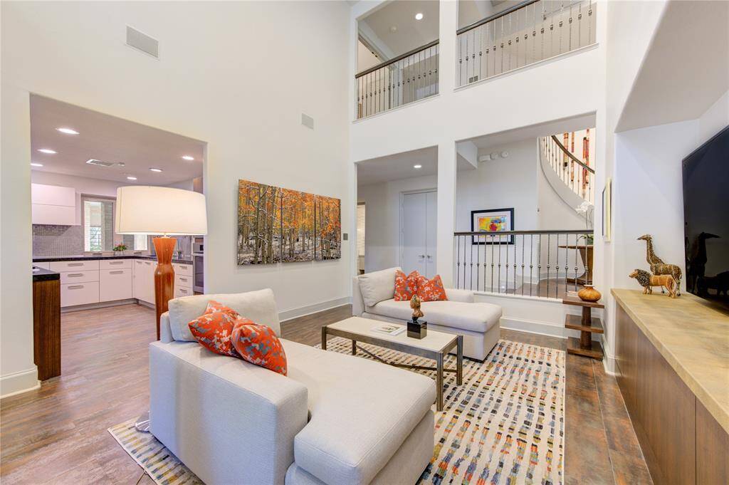 This bright, airy gathering space features 2-story ceilings, modern finishes, and an open layout. It seamlessly connects to a sleek kitchen and showcases a stylish curved staircase. Perfect for contemporary living.