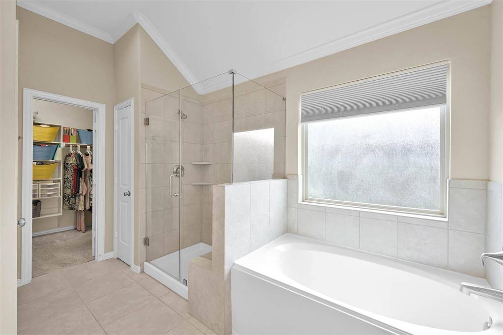 Separate shower with glass enclosure and a large soaking tub completes this room