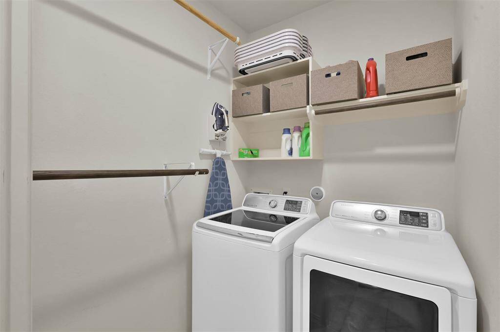 The laundry room is located on the first floor with lots of clothes hanging space & shelves.