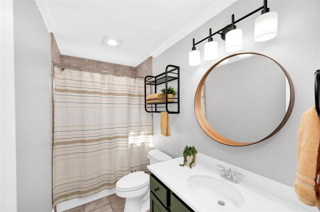 First floor full bath with tub and shower combined, bidet, and stylish round vanity mirror.