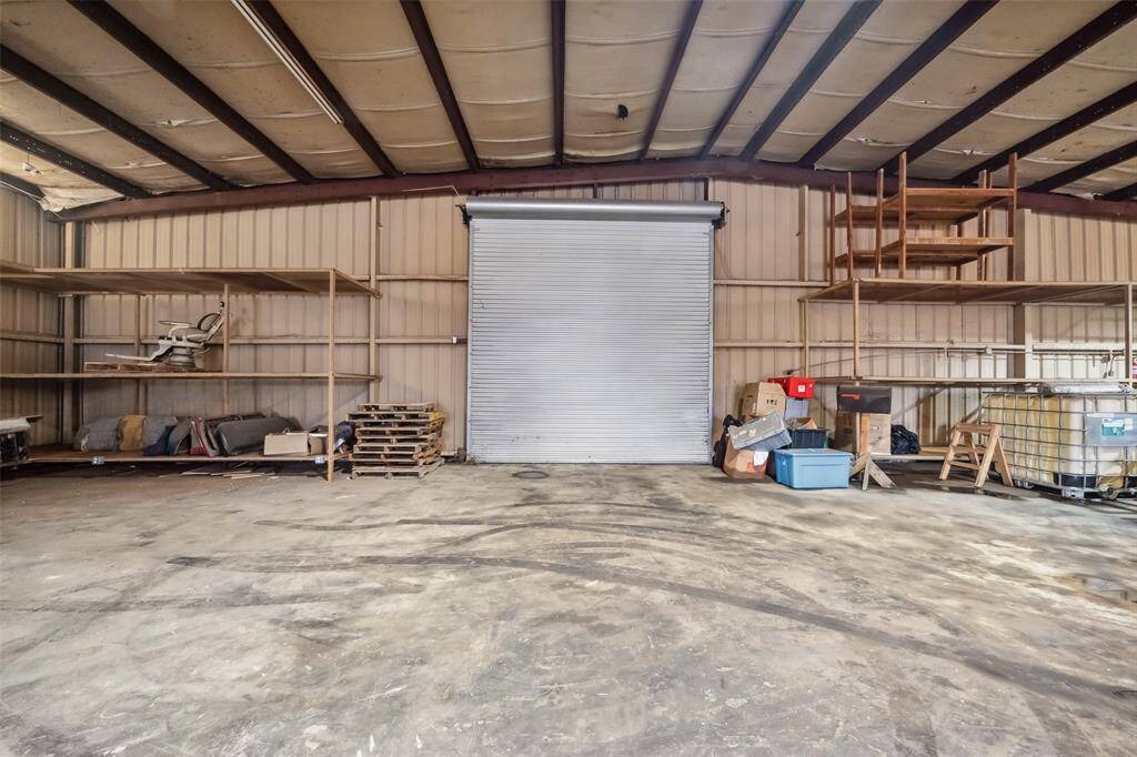 The inside of the warehouse. Notice the ceiling is insulated. It includes shelving units offering ample storage and workspace potential.