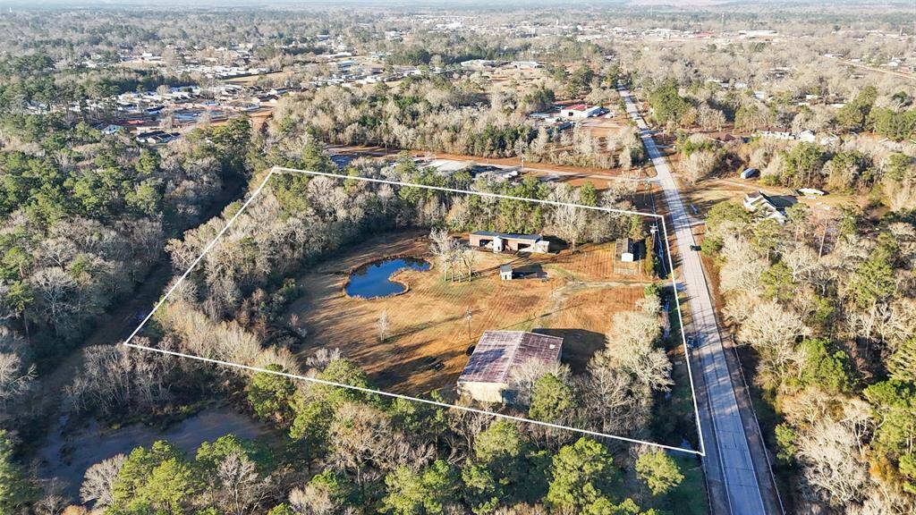 Expansive rural property with a pond, surrounded by trees. Includes multiple buildings and open space, offering privacy and potential for development. Accessible via FM 787 with lots of road frontage.,