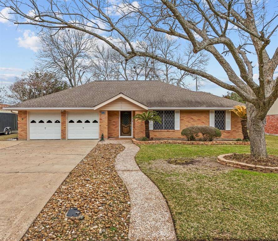 Charming single-story brick home with a two-car garage and a welcoming front path. The yard is landscaped with mature trees and shrubs, offering an inviting curb appeal.