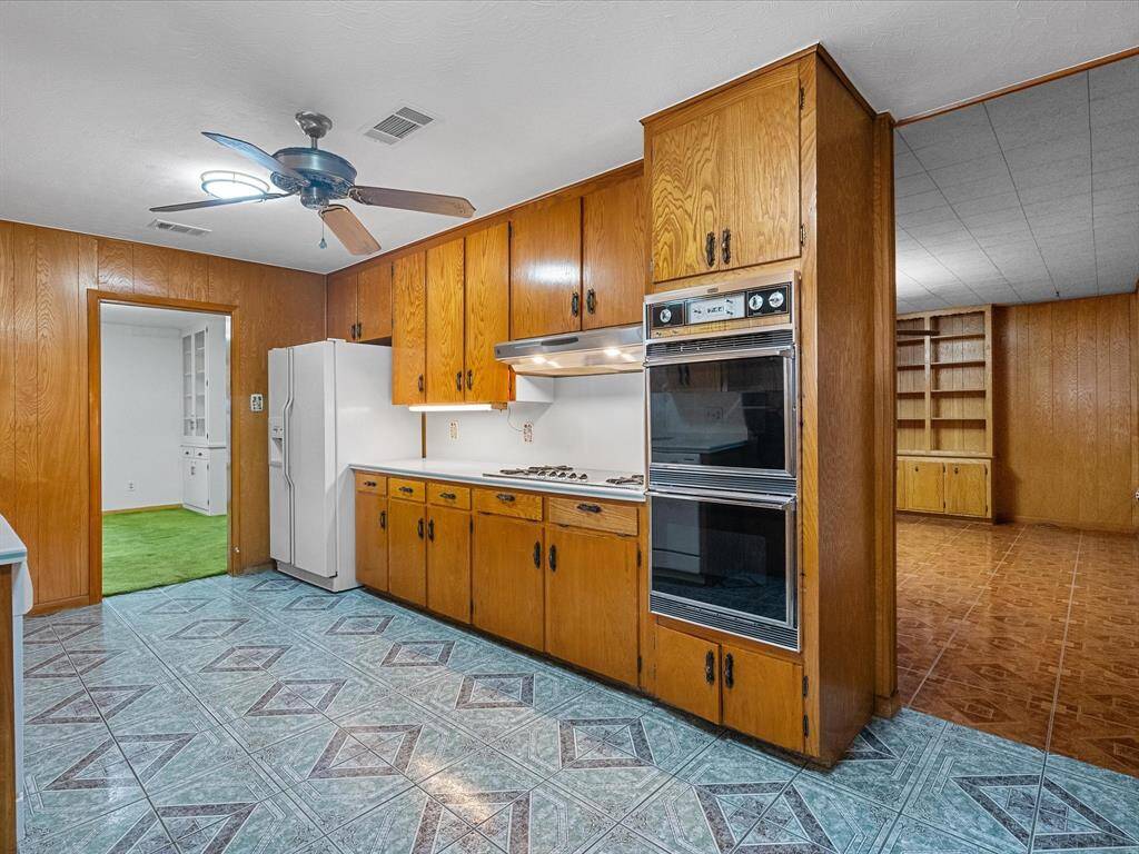 Spacious kitchen flows to/from the formal dining and opens into an adjoining family room/den with built-in shelving.