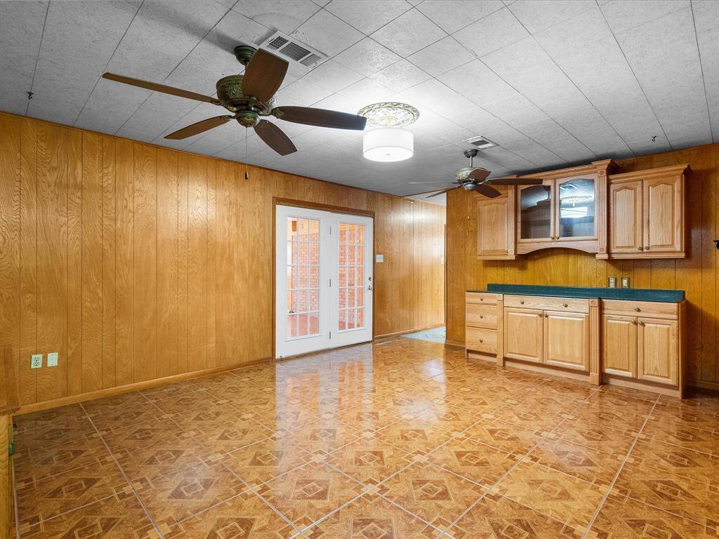 Meticulously cared for wood-paneled walls, gleaming flooring, custom built-ins with lower cabinets; hutch w/upper glass-front cabinets, lower cabinets, drawers, granite countertop, interior cabinet lights, under-counter lighting. French doors lead to another spacious living space.