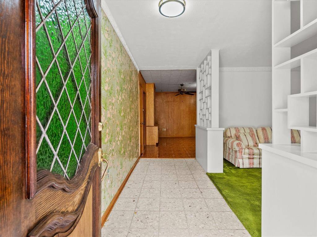Front entryway thru decorative glass paneled door you'll step into a terrazzo tiled foyer. The space to the right opens to carpeted formal living area. Moving forward will lead to a wood paneled family room.