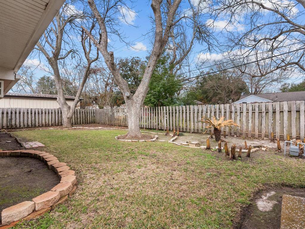 Before the winter frreeezzze of 2025... :(   Spacious backyard featuring mature trees, a wooden fence for privacy, and a small landscaped area with potential for gardening or outdoor activities.