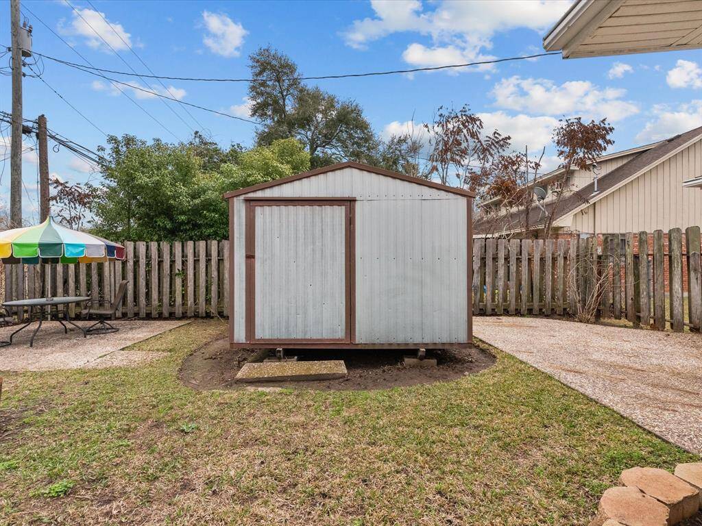 Metal backyard storage shed conveys, adds additional utility space and sits just next to pebbled patio area.