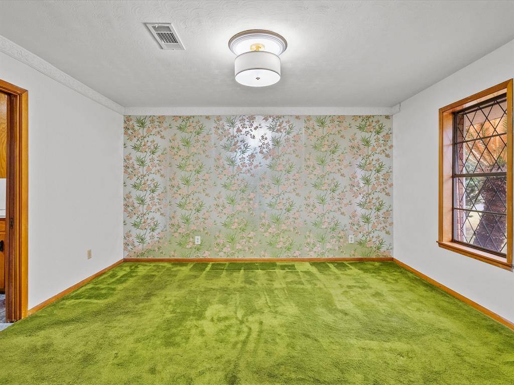 Pretty floral accent wall, complemented by a wood trimmed window, the space is well-lit with the addition of a stylish ceiling light. White walls and a clean design offers potential for personalization.