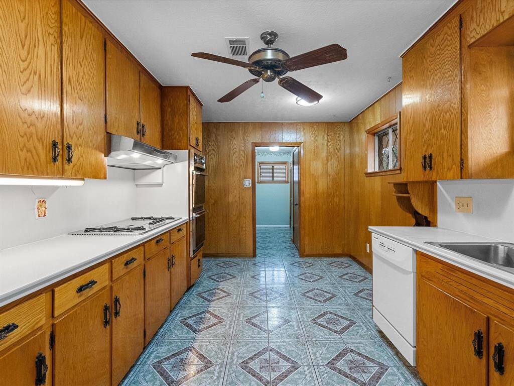 For the chef of the house, the kitchen features wood-paneled walls & cabinets, ceiling fan, and a lovely, unique design tiled floor. Gas cooktop, double oven, dishwasher, ample counter space all offering a classic, functional space.