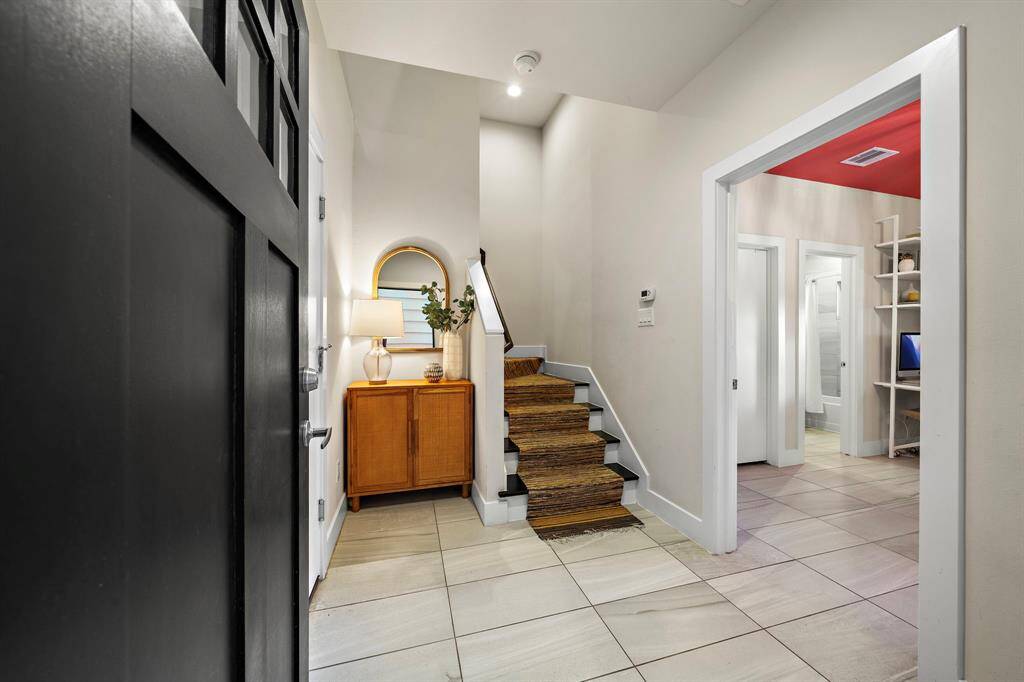 Step into contemporary elegance in this welcoming foyer, featuring sleek tiled flooring and a stylish console that complements the modern design. The space leads to a staircase with rich wood tones, setting the tone for the home's sophisticated ambiance while providing practical access to the upper levels.