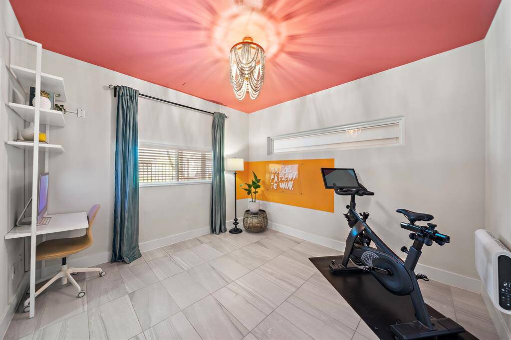 This versatile room combines function and style, suitable for a home office or personal gym. Modern tile flooring, a chic overhead light fixture, and ample natural light enhance its adaptability.