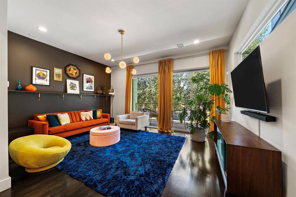 Experience the epitome of contemporary style in this living room, where abundant natural light enhances the space through expansive windows and a private balcony. High ceilings, designer lighting fixtures, and elegant hardwood floors set the stage for seamless indoor-outdoor living and cozy gatherings.