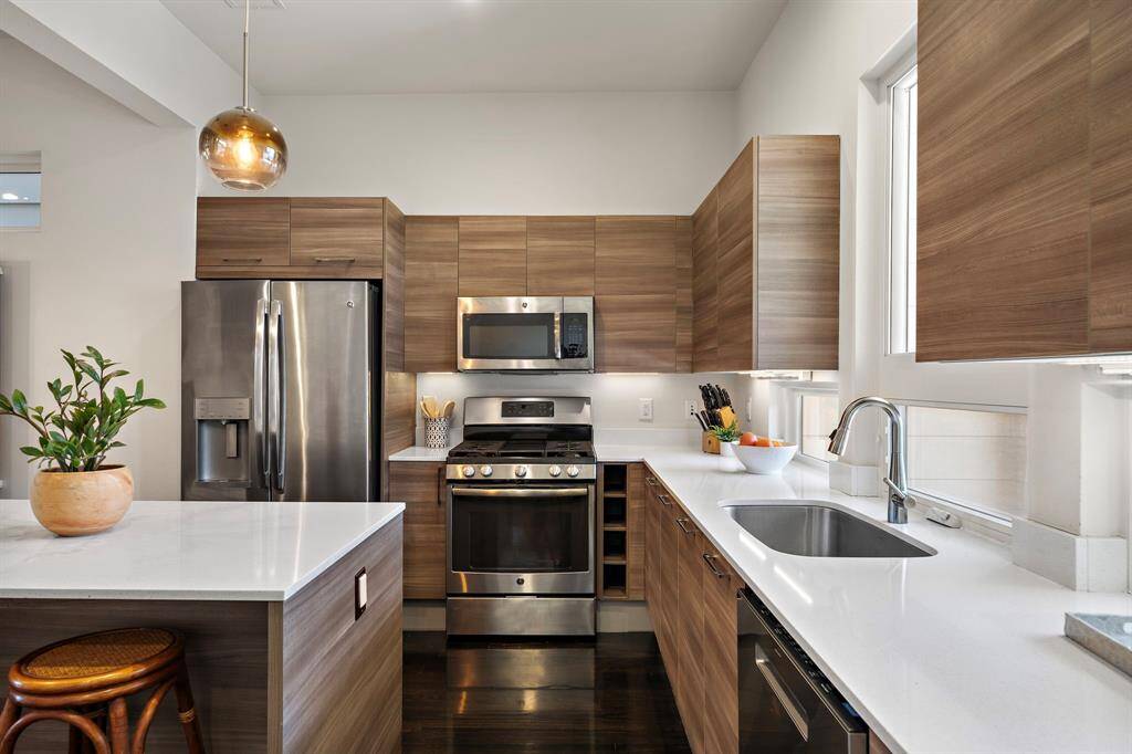 The modern kitchen features a gas range, highlighted by a contemporary backsplash. An expansive island with counter seating complements the dining area, and recessed lighting enhances the bright and welcoming space for culinary endeavors.