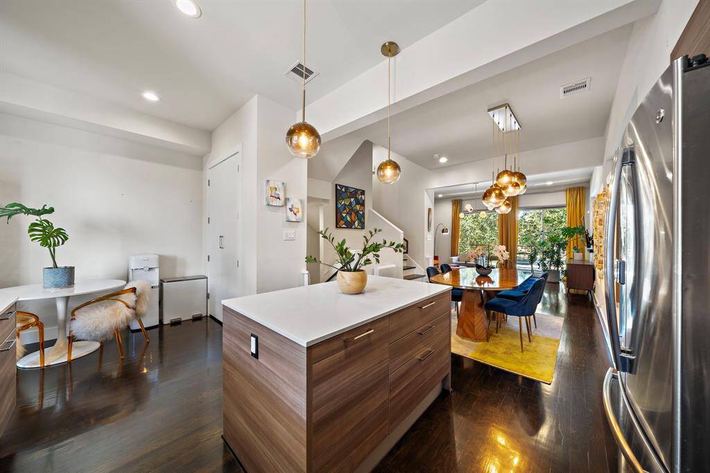 Seamlessly combining contemporary style with functionality, this kitchen and dining area feature a sleek central island. Designer lighting and hardwood floors enhance the modern aesthetic, while direct access to the dining space ensures easy entertaining and casual meals.