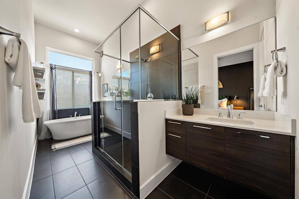 Discover the primary bath's contemporary elegance with a glass-enclosed shower and luxurious soaking tub. The dual sink vanity offers ample space, while sleek tile flooring and modern finishes enhance this serene retreat. Ideal for relaxation and unwinding, it epitomizes sophisticated comfort.