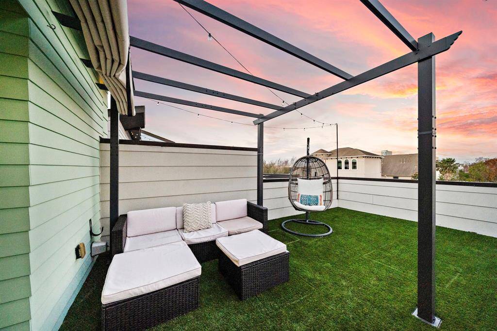 Relax on the rooftop terrace, featuring a pergola and inviting seating area. This expansive space allows for entertaining or unwinding, with string lights adding charm. The low-maintenance turf enhances outdoor enjoyment and offers serene views of the vibrant surroundings.