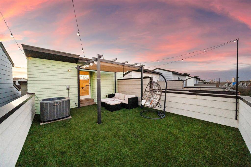 Unwind on this modern rooftop terrace with lush low-maintenance turf and a cozy seating area under a chic pergola. Ideal for entertaining or serene relaxation, the space features charming string lights, enhancing the ambiance.