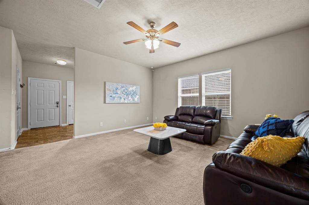 This living room features neutral walls, plush carpeting, and ample natural light from two windows.