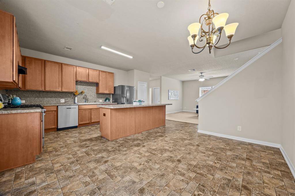This photo showcases a spacious open-plan kitchen and dining area. The kitchen features warm wood cabinetry, modern stainless steel appliances, and a large central island for extra seating.