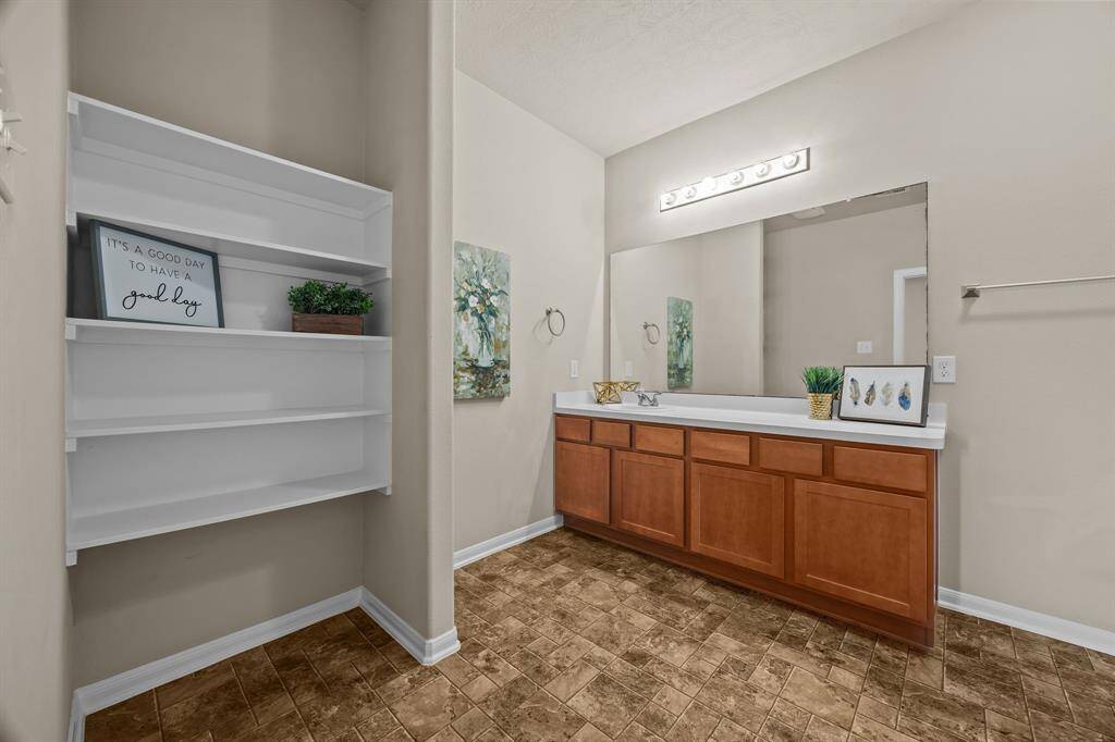 Spacious primary bathroom featuring ample shelving and an expansive vanity.