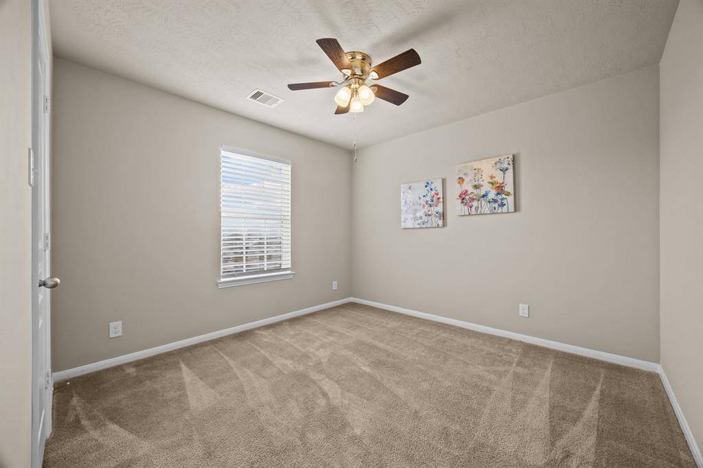 Charming third bedroom featuring soft carpet, abundant natural light, and a stylish ceiling fan. Ideal room for friends or family.