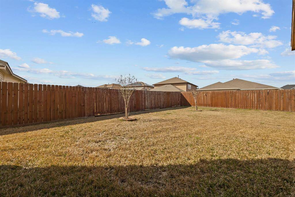 Spacious backyard with a well-maintained lawn, surrounded by a wooden privacy fence. Ideal for outdoor activities and gardening.