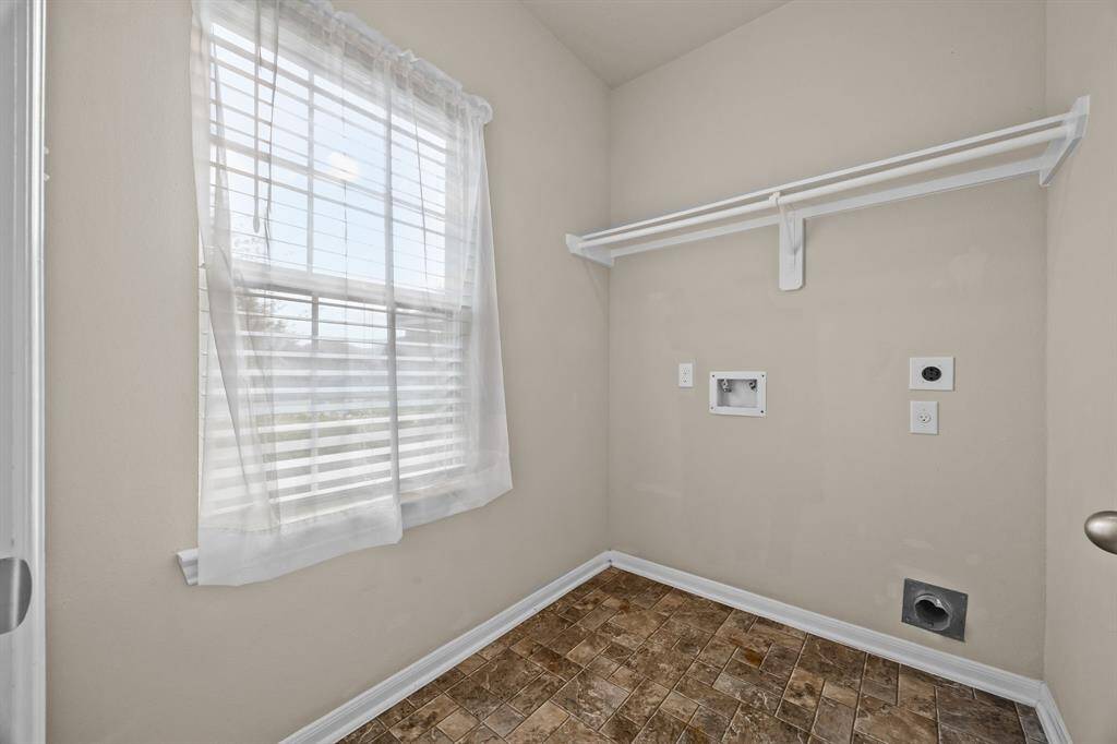 Efficient laundry room with ample natural light and convenient shelving.