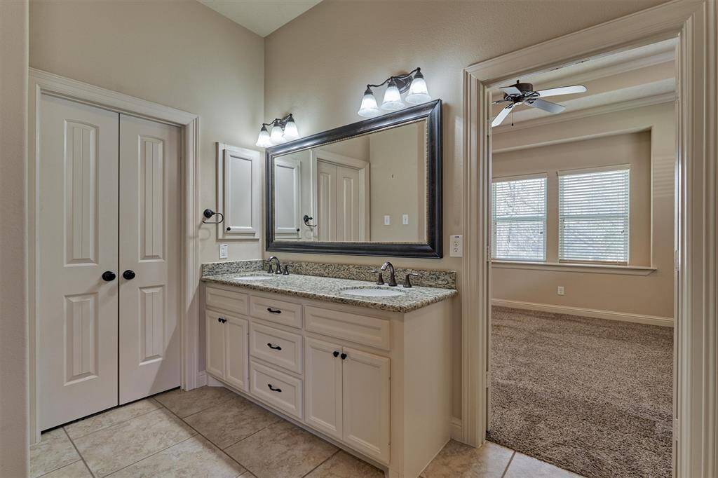 Double sinks with vanity for extra storage. Double doors lead to the primary closet.