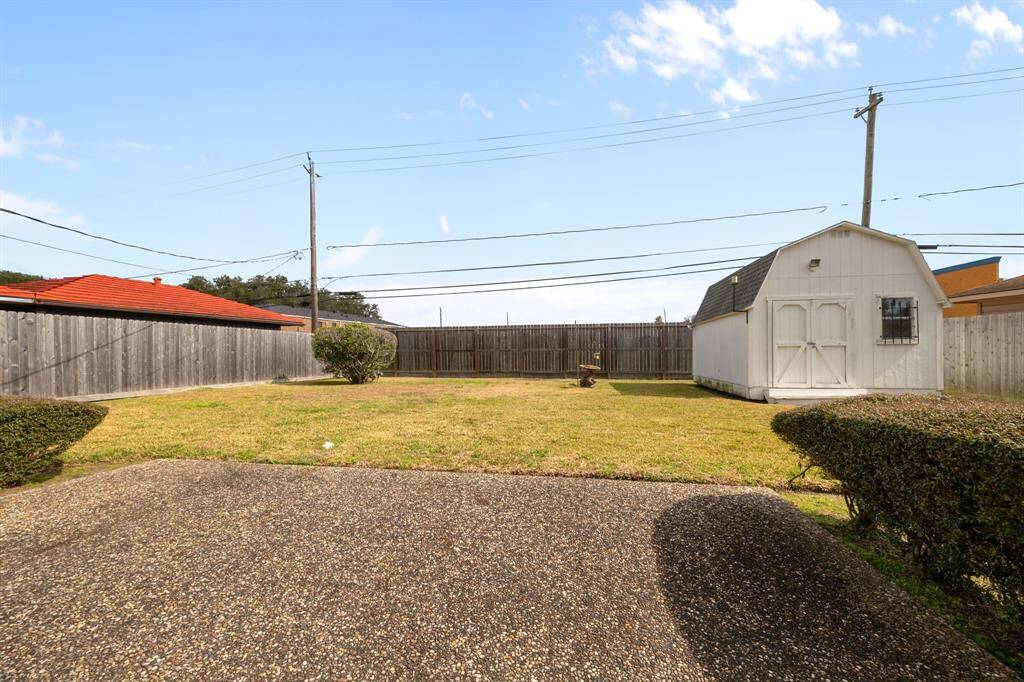 Spacious Backyard with a well-maintained lawn, privacy fencing, and a large Storage Shed. Ideal for outdoor activities and storage needs.