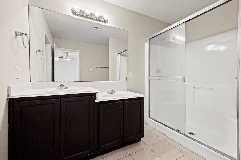 Dual vanities offer personal space with tons of dedicated cabinet space. Expansive walk-in shower invites refreshment.