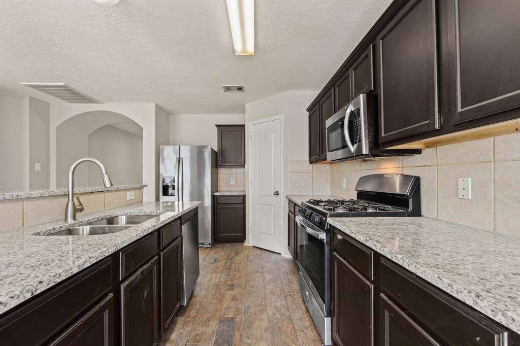 Your chef inspired kitchen awaits! Features include easy care countertops paired with a coordinating stone backsplash, stainless steel appliances, rich cabinets, tons of lighting, and a sprawling island with breakfast bar seating.