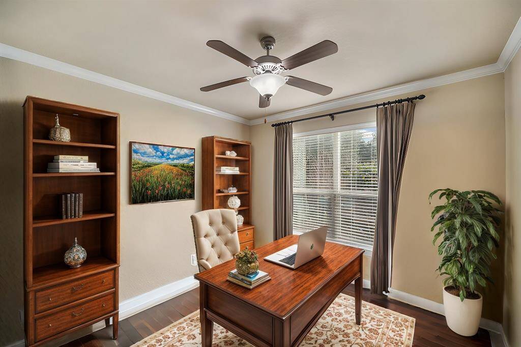 The home office offers rich wood floors and elegant crown molding, creating a polished and productive atmosphere. Double French glass doors provide both privacy and an open, airy feel.
