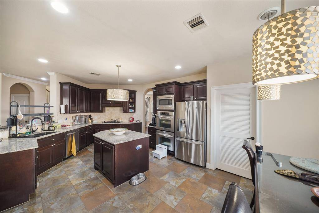 The kitchen is a chef’s dream, featuring a spacious island perfect for meal prep. Equipped with double ovens, a built-in microwave, and a gas cooktop, this well-appointed space combines convenience with functionality.