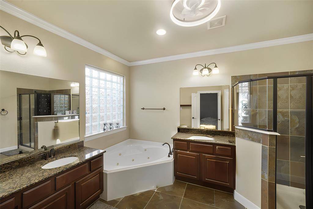 The primary ensuite offers a spa-like experience with dual vanities, whirlpool tub, and a separate shower. A private water closet and a spacious walk-in closet complete this luxurious, functional retreat.