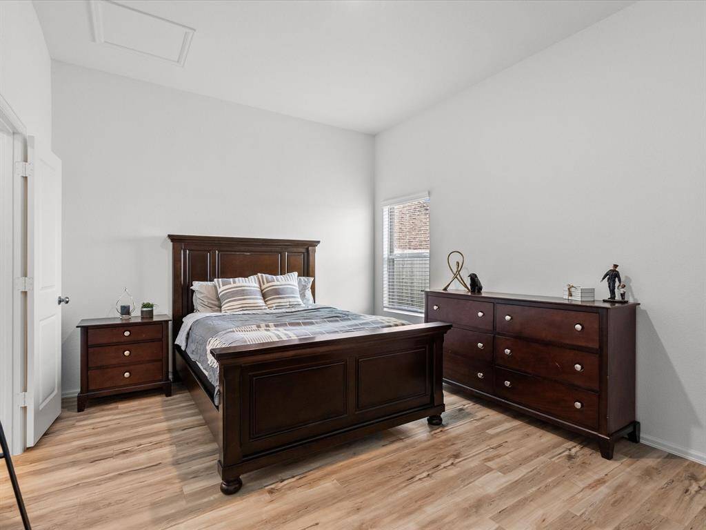 Relax in the spacious primary bedroom, featuring sleek luxury vinyl plank flooring and large windows.