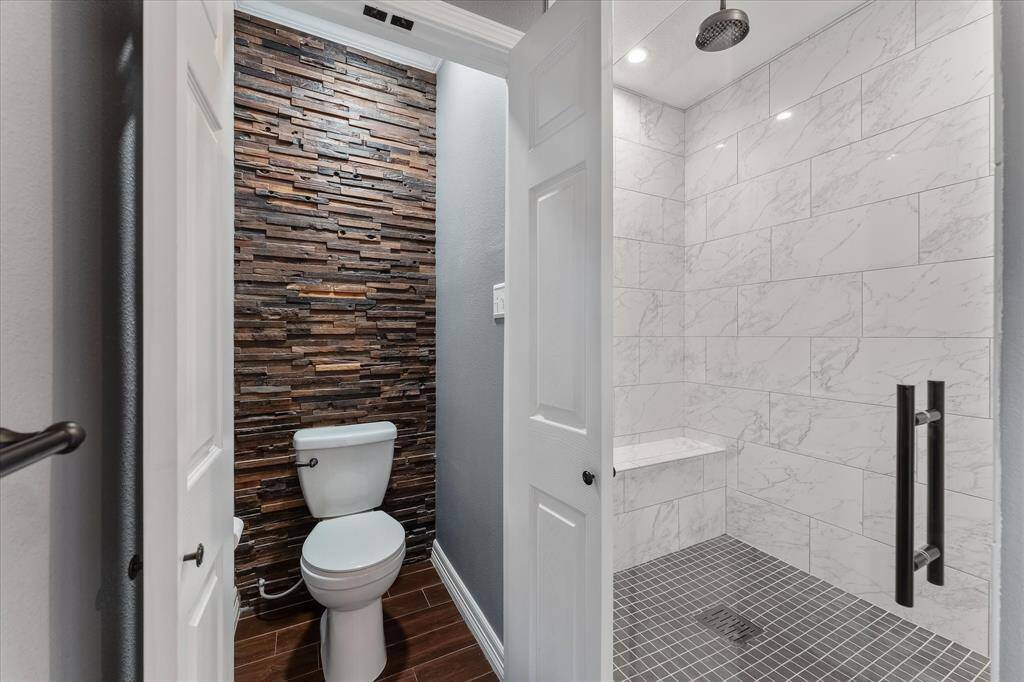 Spacious primary shower with bench and rain shower head.