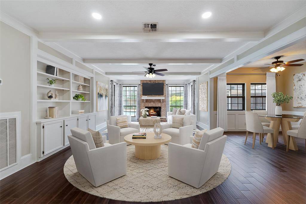 The spacious living room features custom built-ins, beamed ceiling, gas log fireplace, opens to breakfast room and wet bar. Virtually Staged.