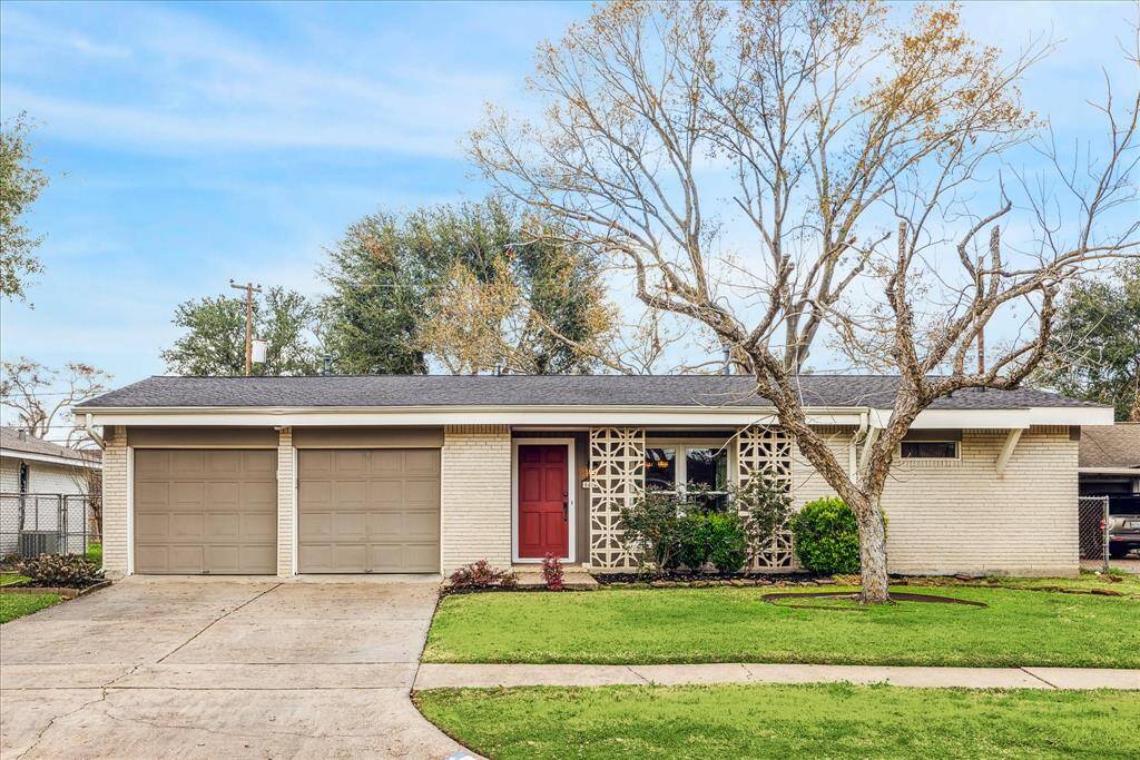 This charming single-story home features a two-car garage, and a decorative brick facade with greenery.
