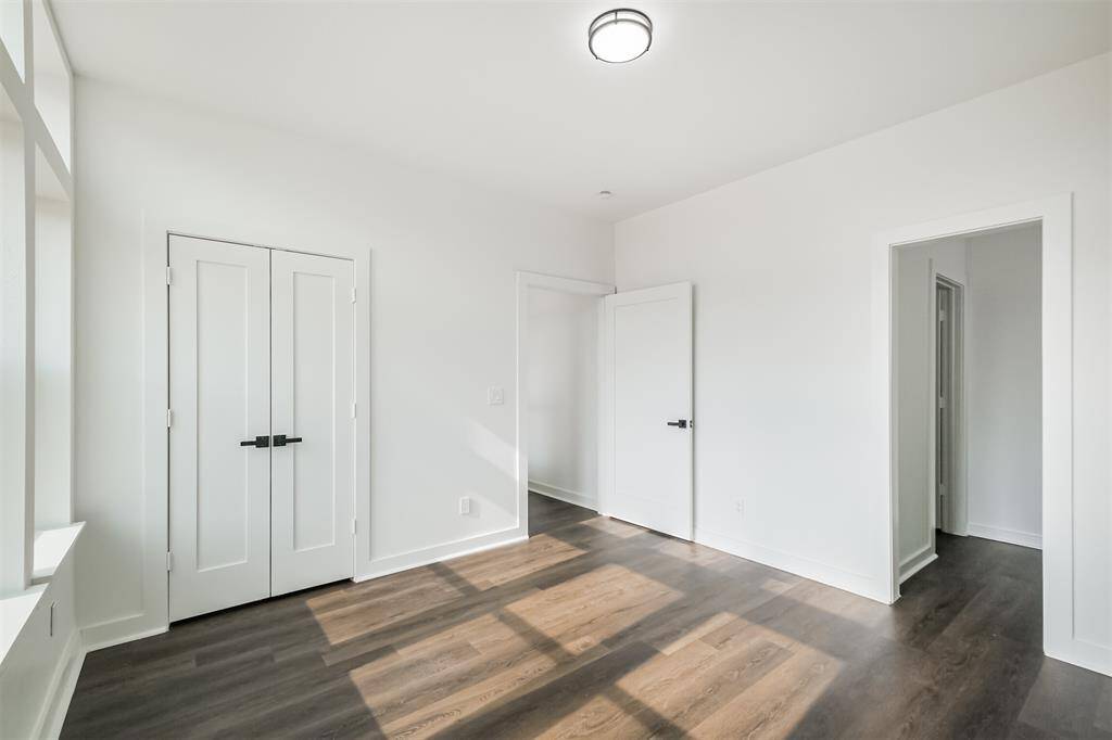 Bright room with large windows, neutral walls, and dark wood flooring, offering ample natural light and a modern feel.