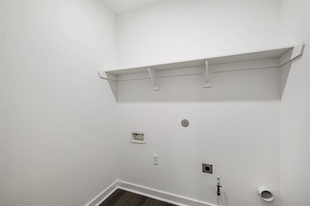 This room features sleek hardwood flooring and clean white walls, offering a modern and bright space. Recessed lighting adds a contemporary touch, and a door leads to an adjacent area, enhancing functionality.